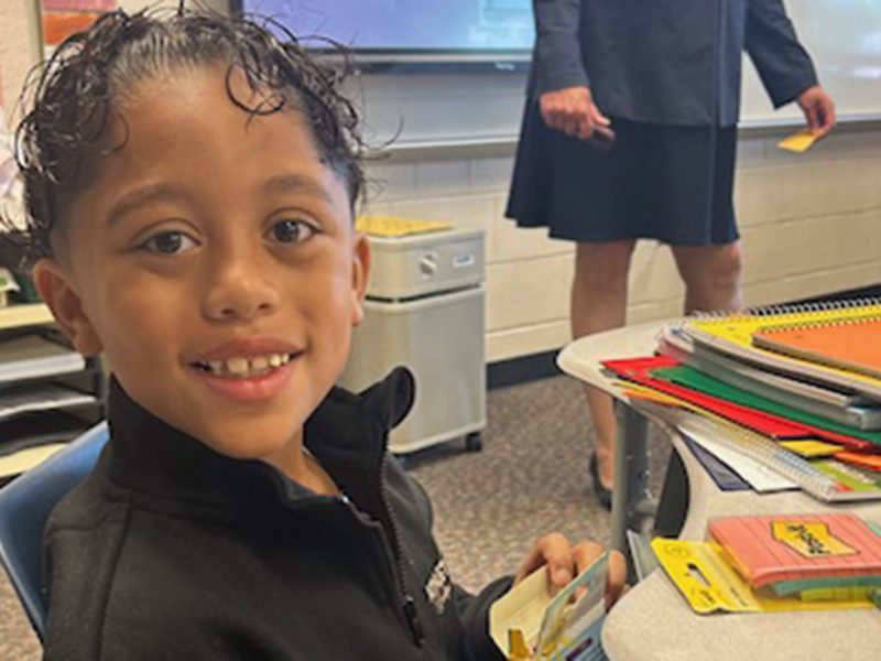 Elementary student in the classroom working on a project and smiling