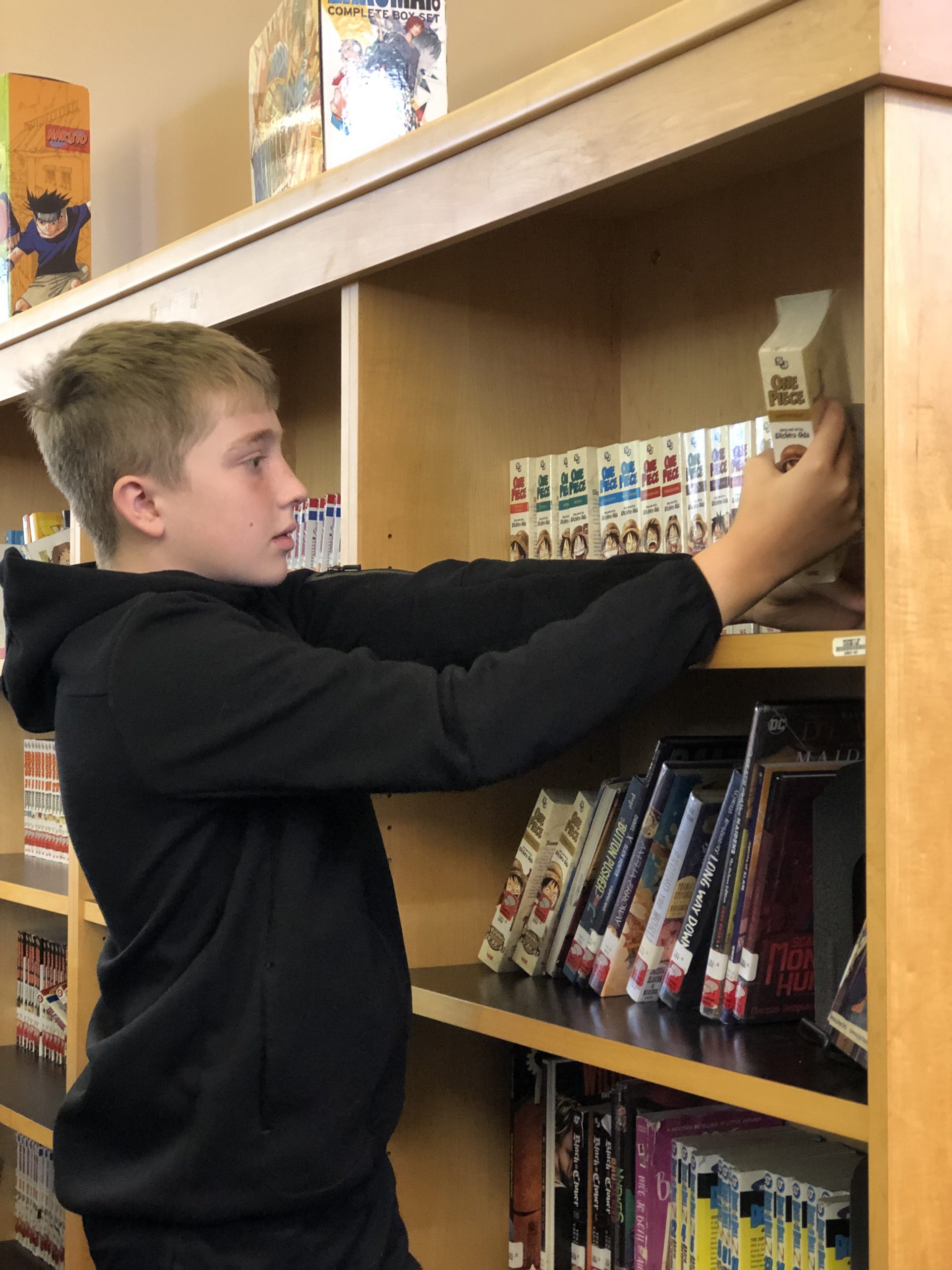 middle school student takes book off shelf