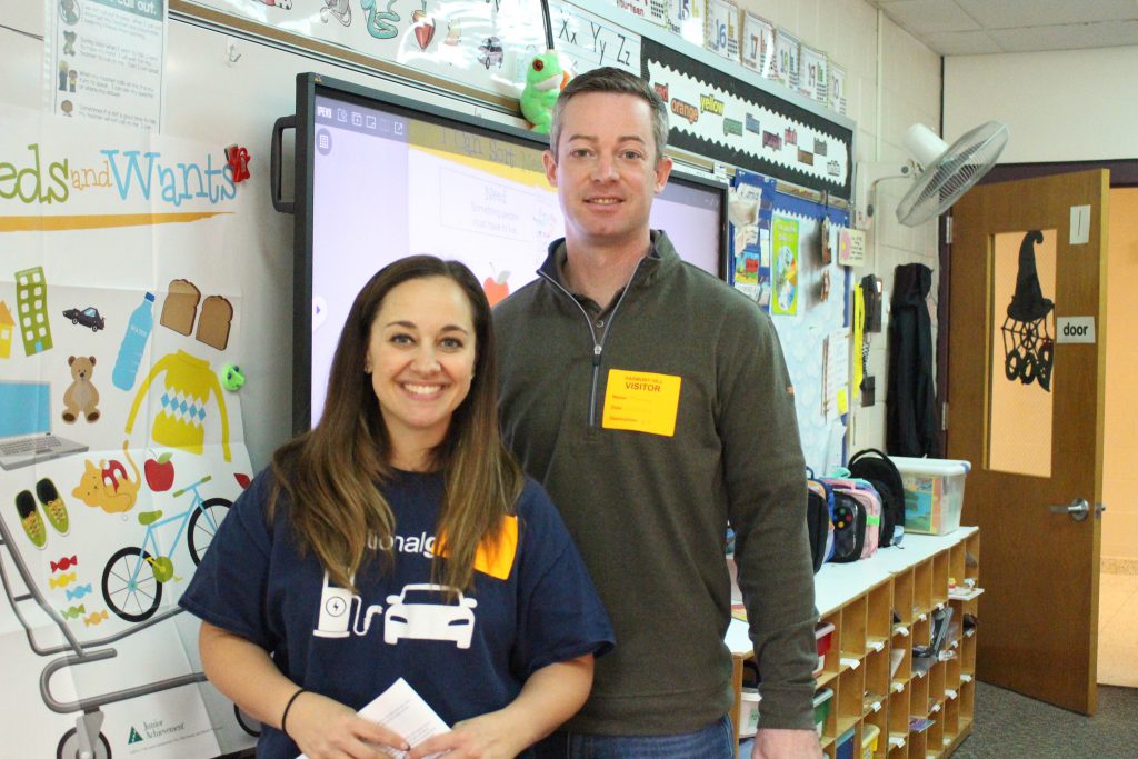 Two visiting community members stand together in the classroom.