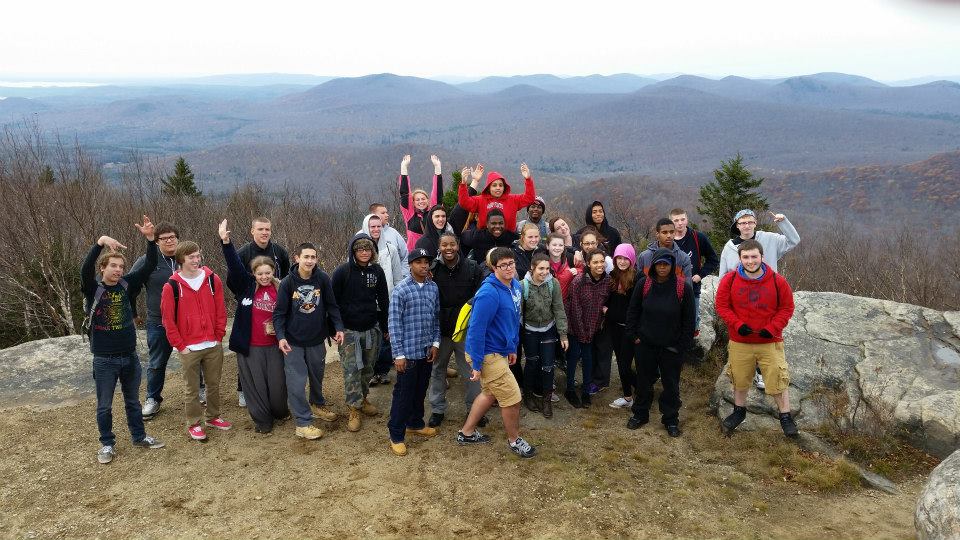 A large group of high school students gather together on the summit of Hadley Mountain.