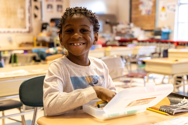 An elementary school student takes writing tools out of his pencil box.