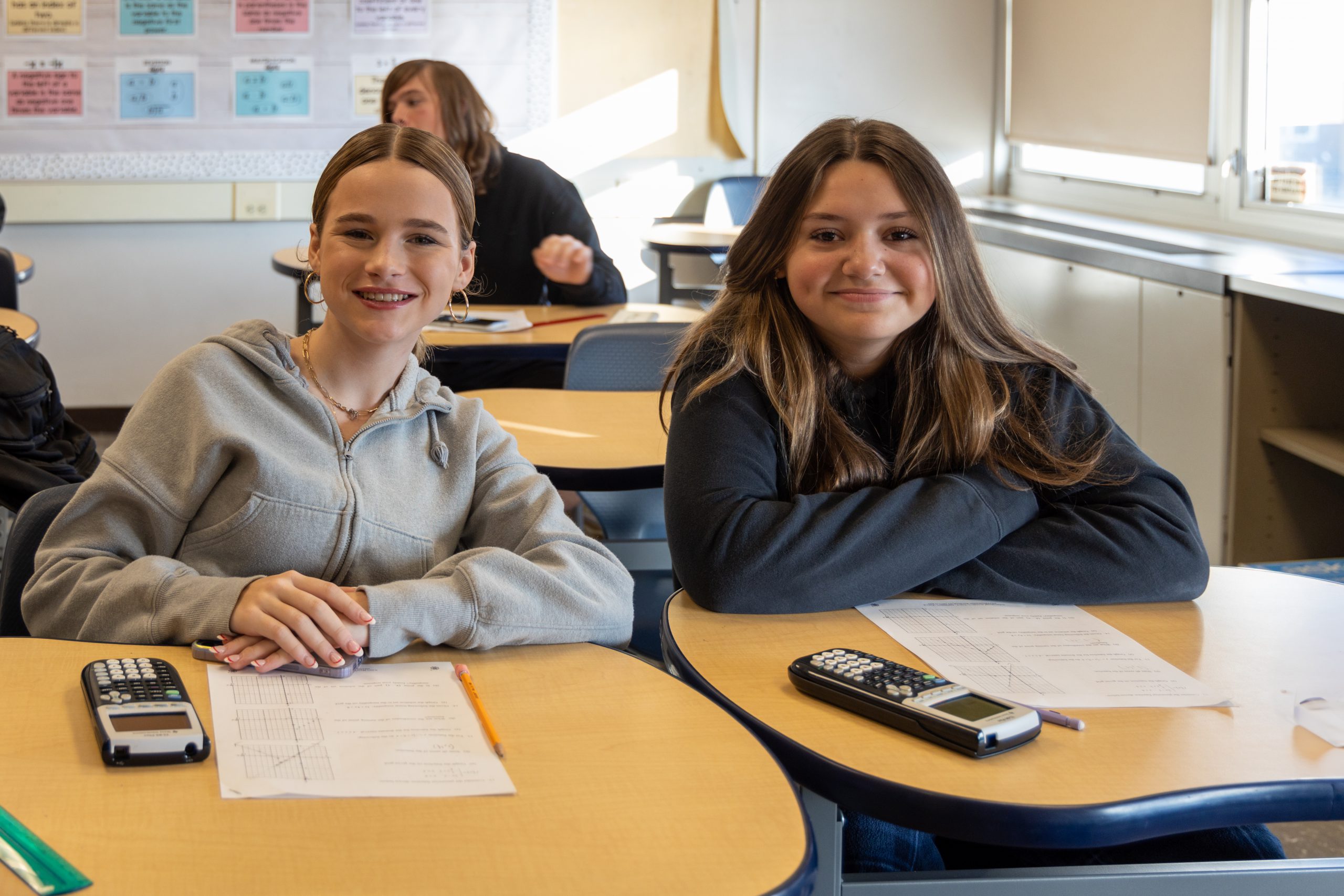 two high school students smile in class