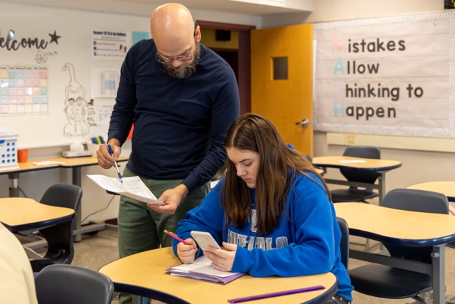 teacher assists high school student with classwork.