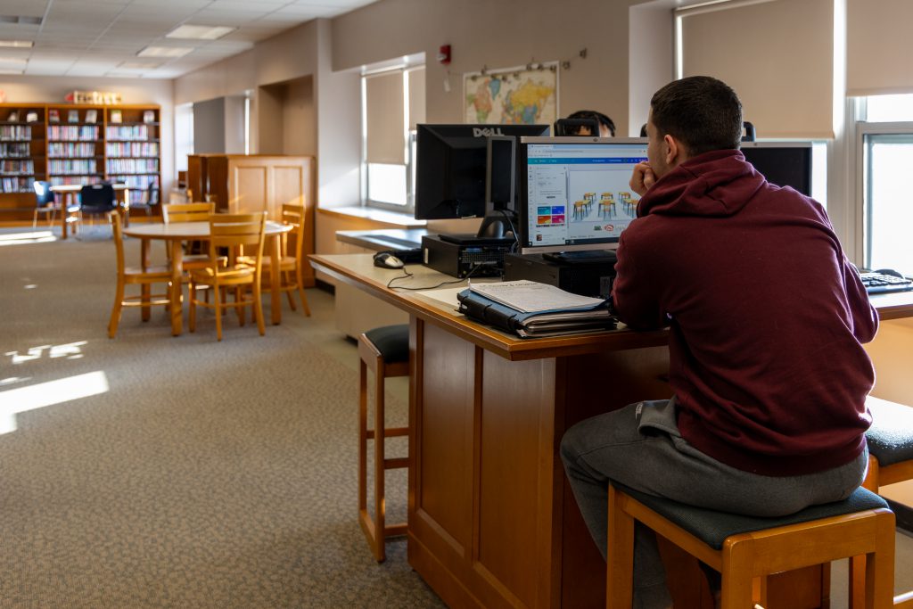 image student working on a computer in the High School library