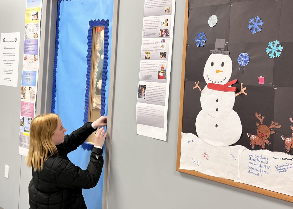 Dayna Spizowski happily decorating a class door with blue paper.